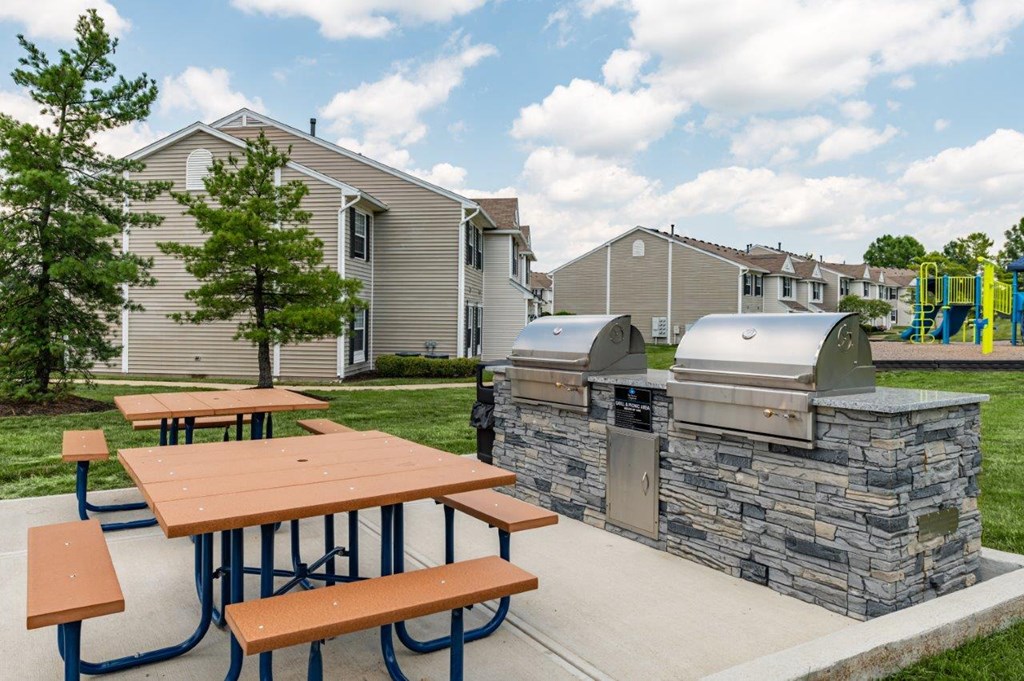a picnic area with a grill and picnic tables