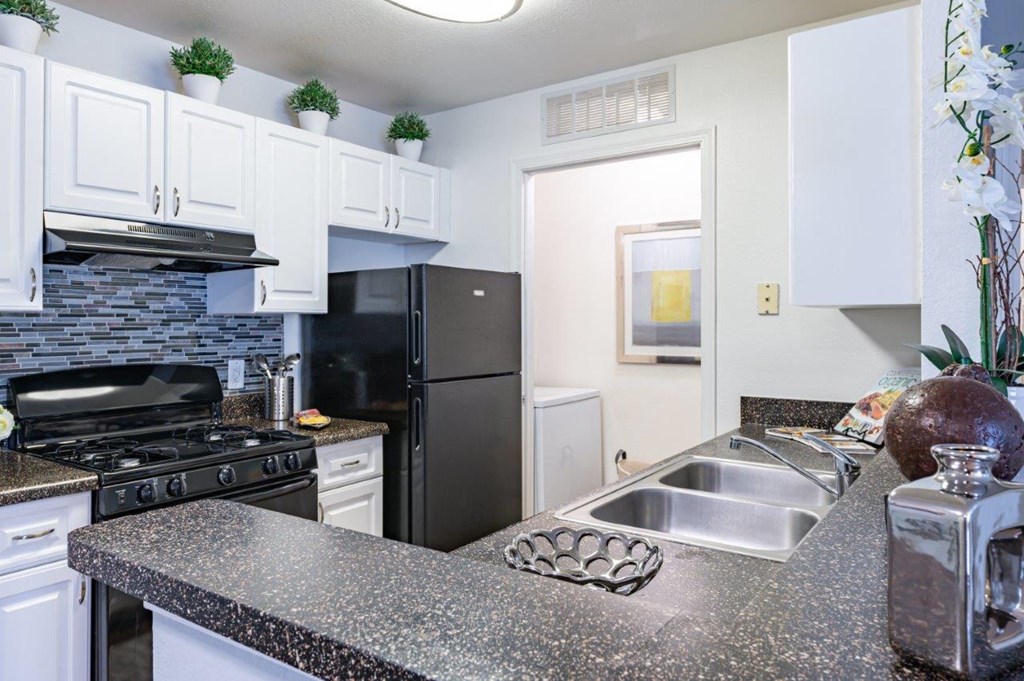 a kitchen with granite counter tops and a black refrigerator