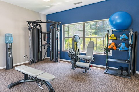 a gym with weights and equipment in a room with a window