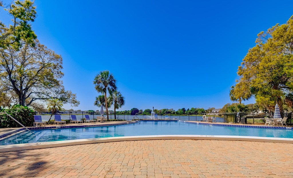 a swimming pool with trees and a blue sky above it
