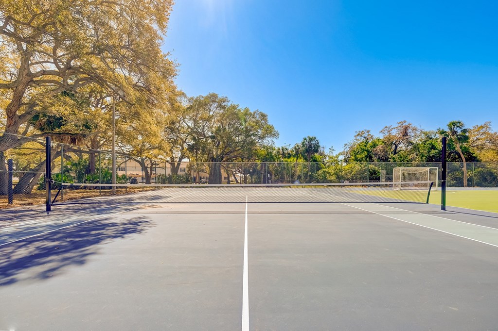 a tennis court with trees in the background on a sunny day