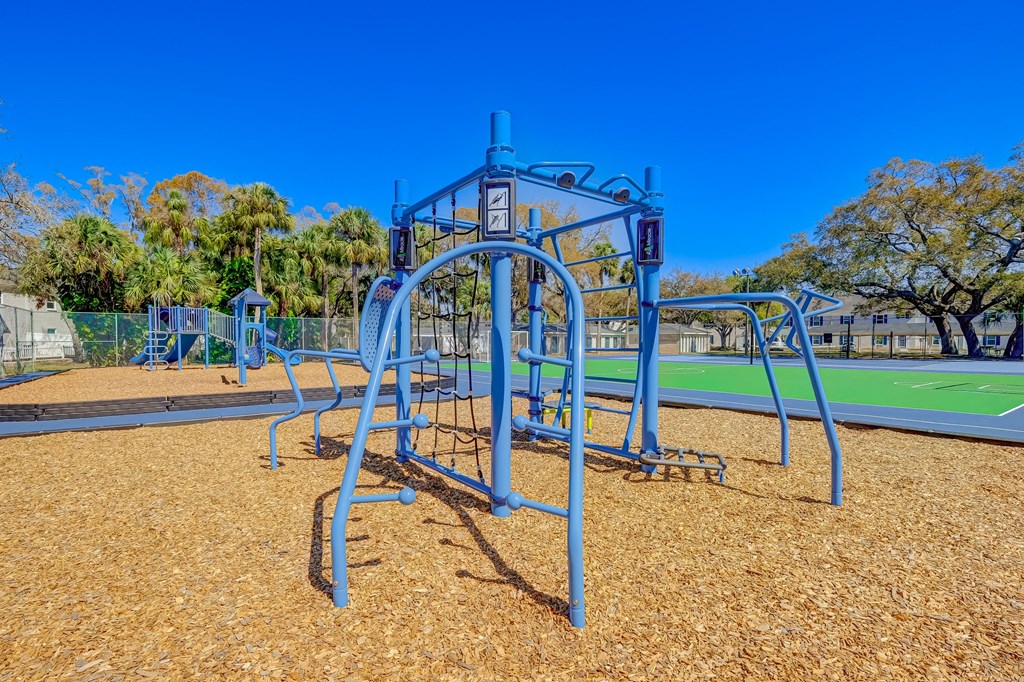 a swing set at a playground with a tennis court