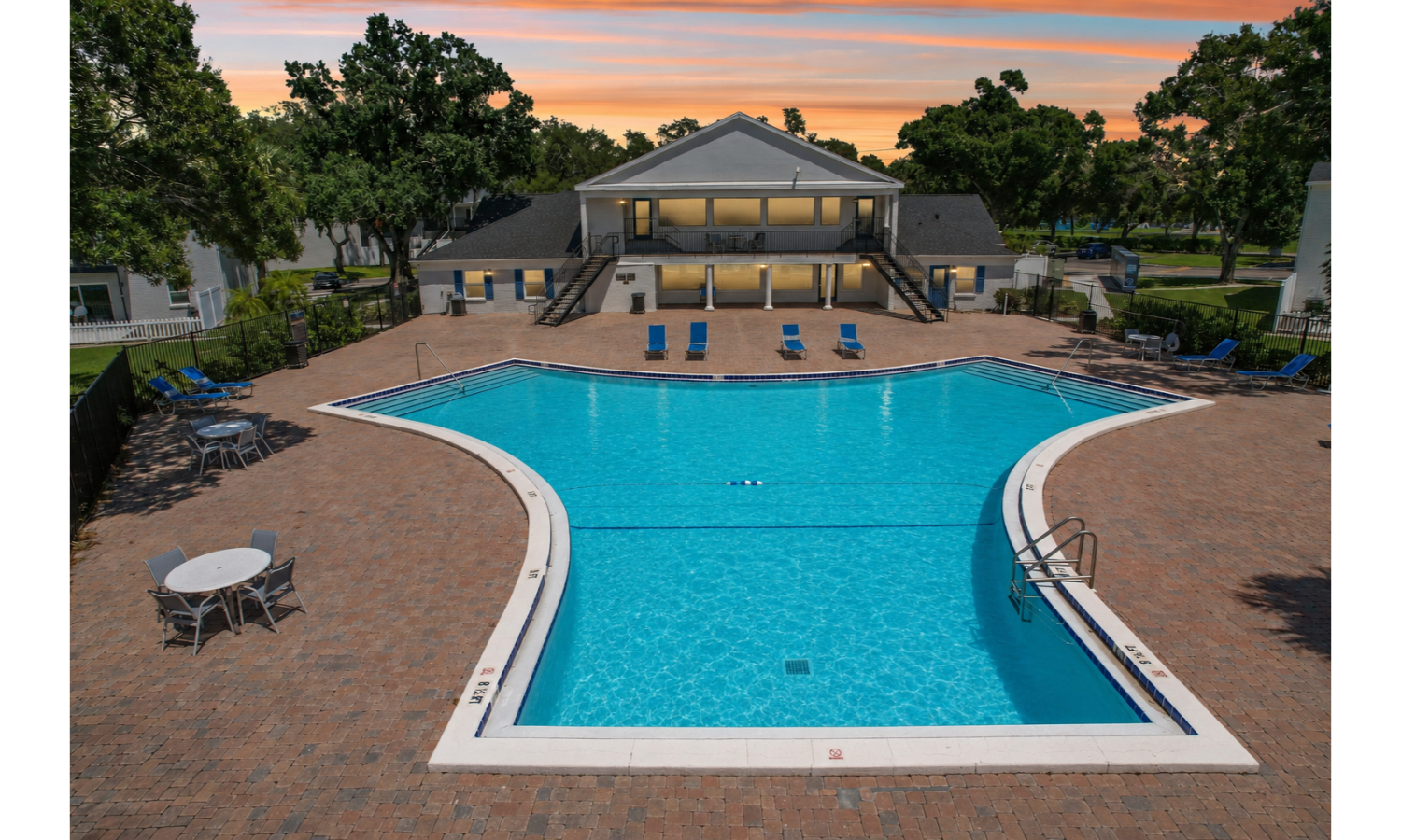 A large swimming pool surrounded by a brick patio and a house in the background.