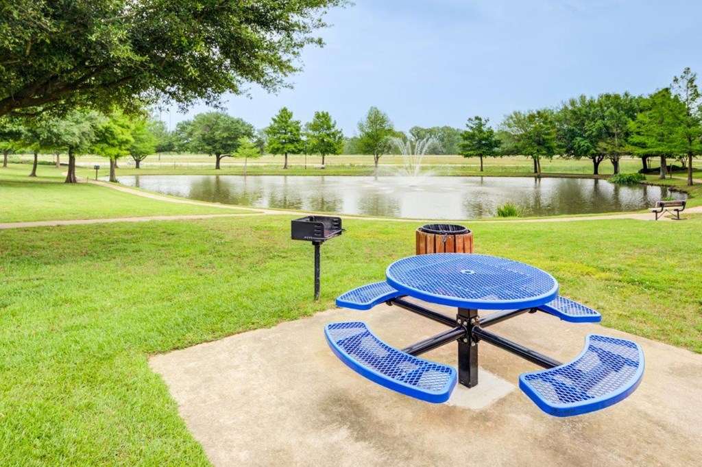a picnic area with a blue picnic table and a grill