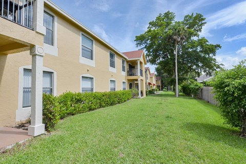 a row of yellow houses with a green lawn and trees