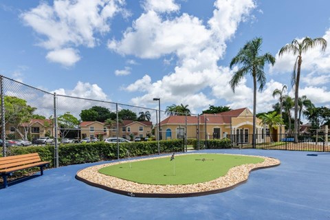 a golf course with palm trees and a bench