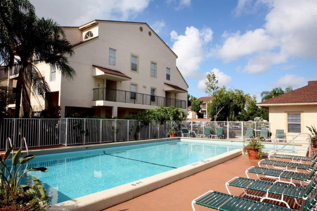 a swimming pool with chairs in front of a building