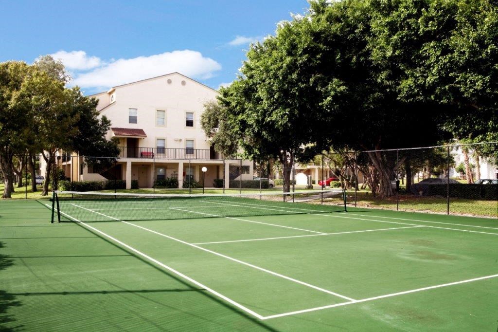 a tennis court in front of a building with trees