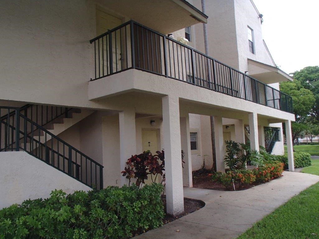 the outside of an apartment building with a sidewalk and plants