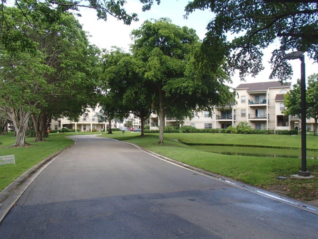 an empty street in a park with trees and apartment buildings