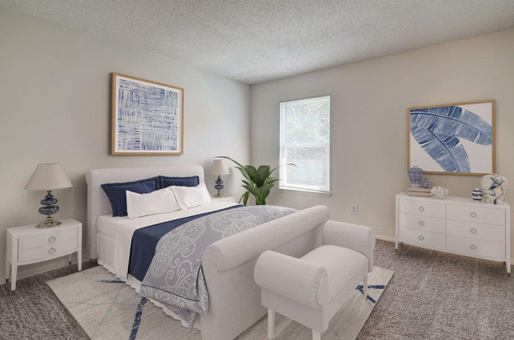 A bedroom with a white bed, a white chair, and a white nightstand.