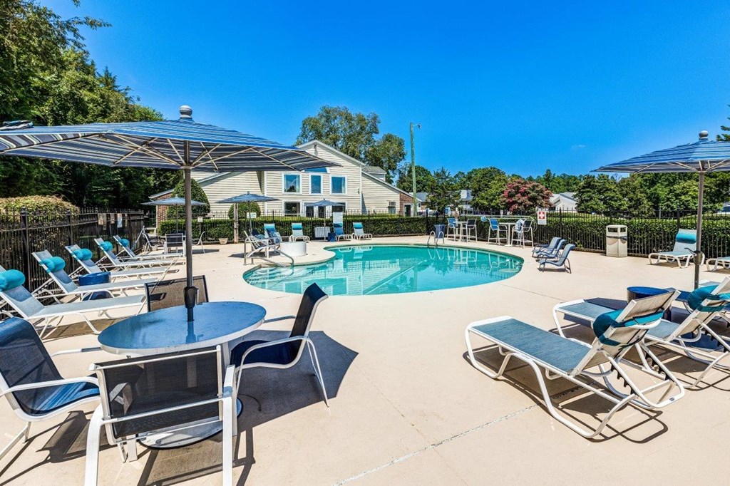 A pool area with chairs and a table.