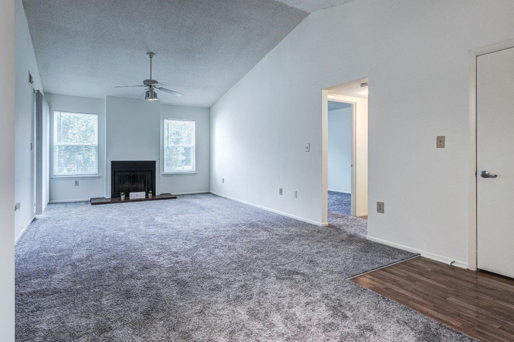 A spacious living room with a fireplace and a ceiling fan.