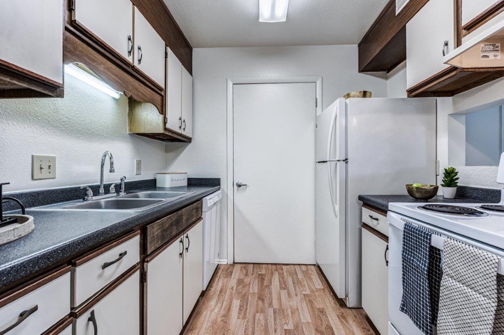 A kitchen with white appliances and wooden cabinets.