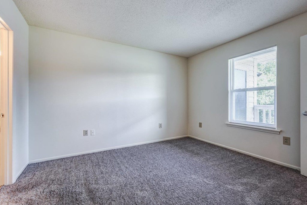 A room with a carpeted floor and a window.