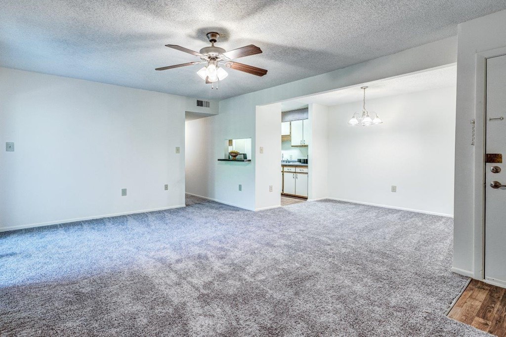 A spacious room with a ceiling fan and carpeted floor.