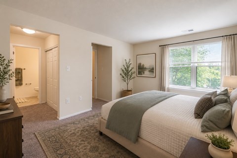 A bedroom with a large bed and a window overlooking trees.