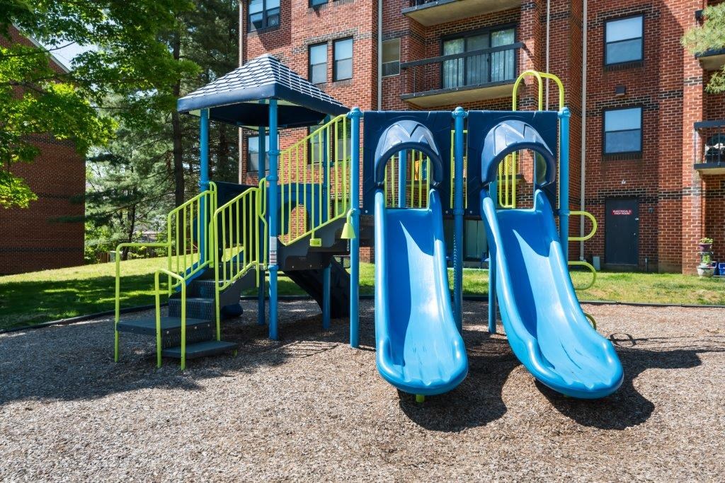a playground with two slides in front of a building