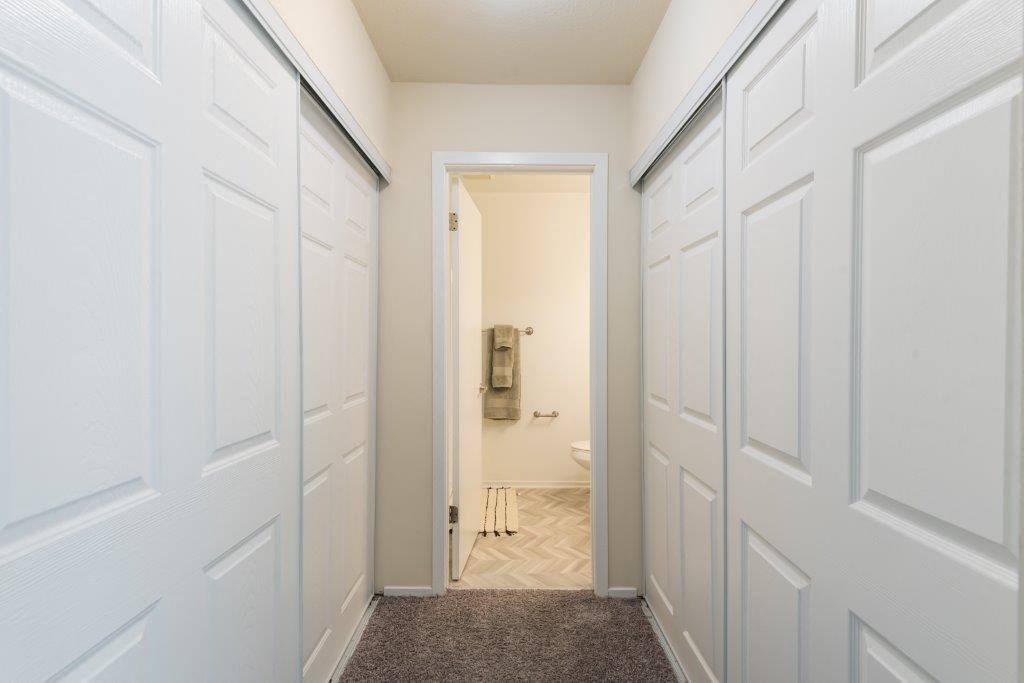 a white hallway with white doors and a white bathroom