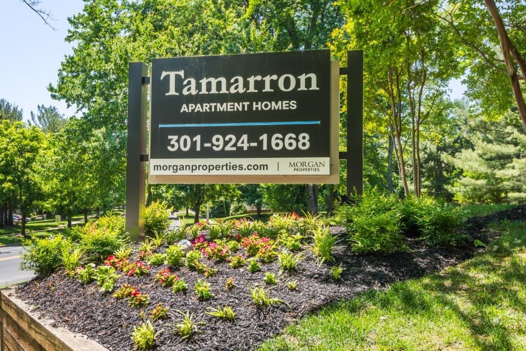 a sign for tamaraton apartment homes in front of a garden