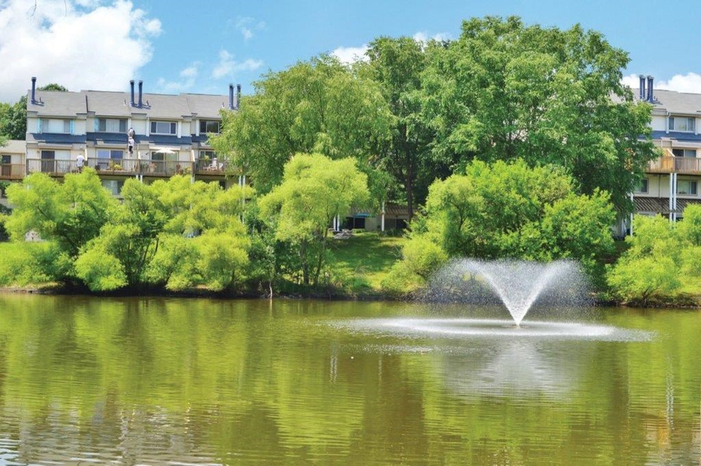 a fountain in the middle of a lake in front of a building