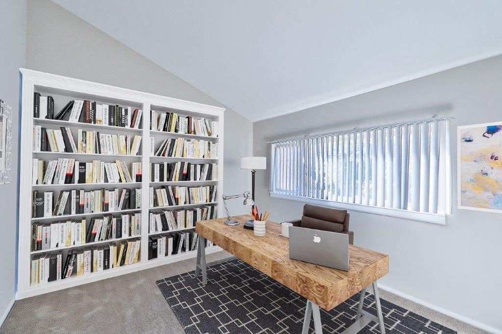 a home office with a large book shelf and a laptop on a desk