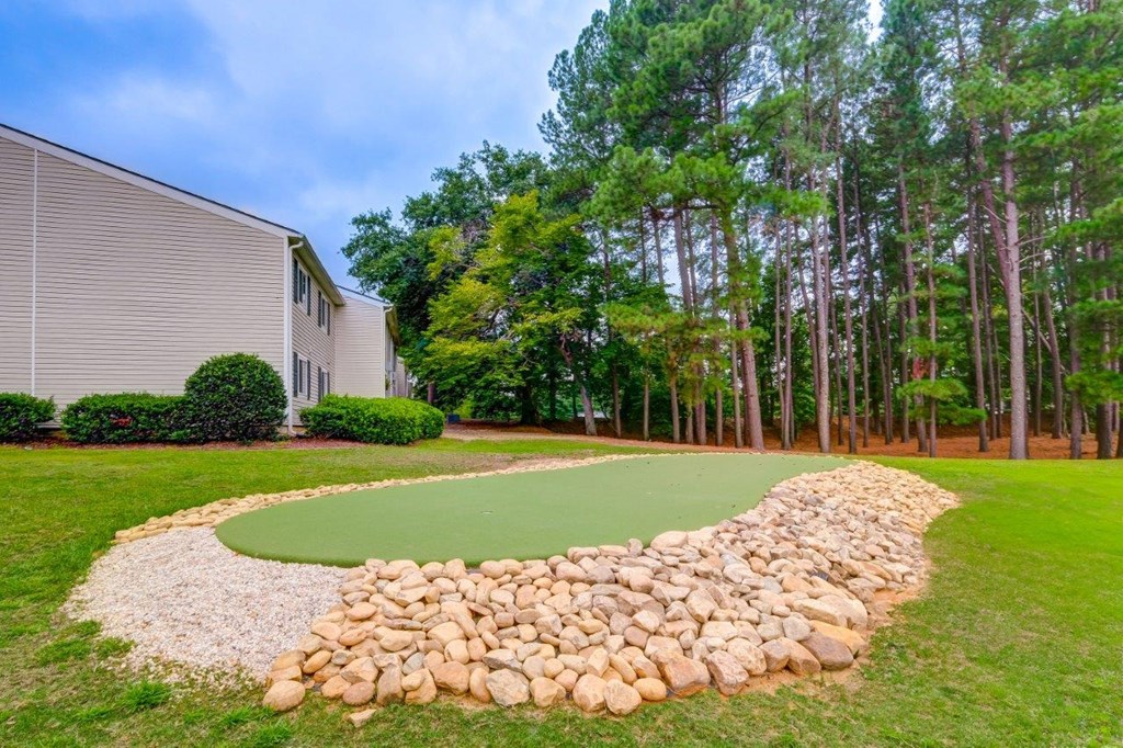 a putting green in a yard next to a house