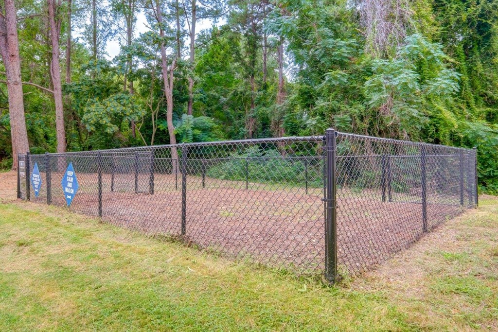 a chain link fence with a gate in front of some trees