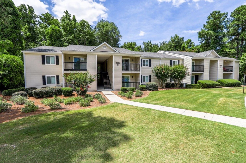 the view of an apartment building with a lawn and trees