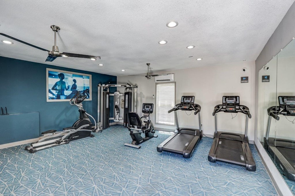 a gym with cardio machines and a tv