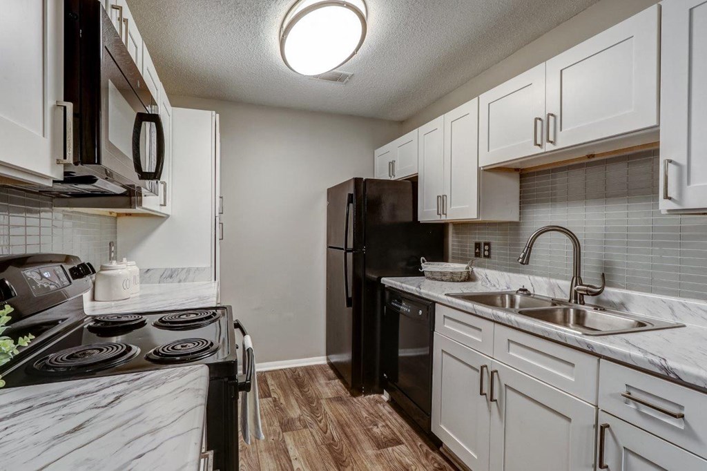 an empty kitchen with white cabinets and a black refrigerator