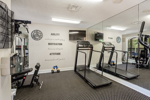 a gym with exercise equipment and a tv on the wall