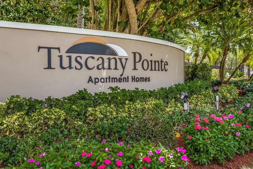 a sign for tuscany pointe apartments in front of flowers