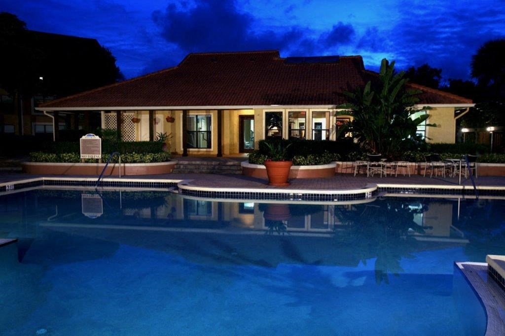 a large swimming pool in front of a hotel at night