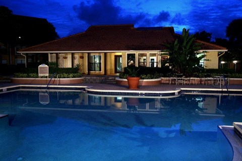 a large swimming pool in front of a hotel at night