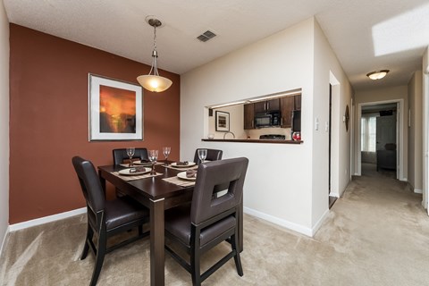 a dining room with a table and chairs and a hallway with a kitchen