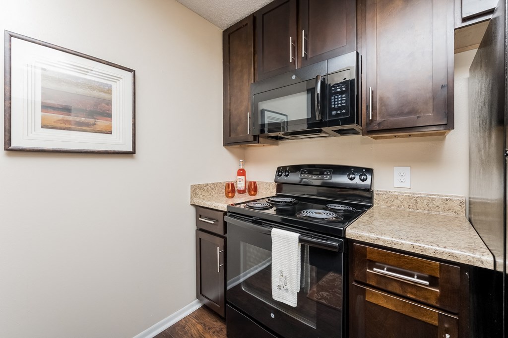 an updated kitchen with black appliances and a granite counter top