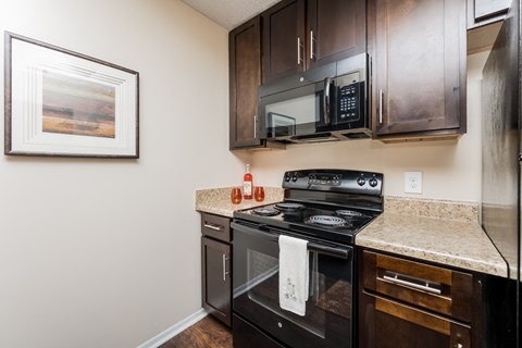an updated kitchen with black appliances and a granite counter top