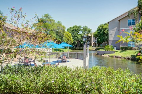 a canal with a patio with chairs and umbrellas