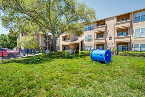 a yard with a blue barrel in front of an apartment building