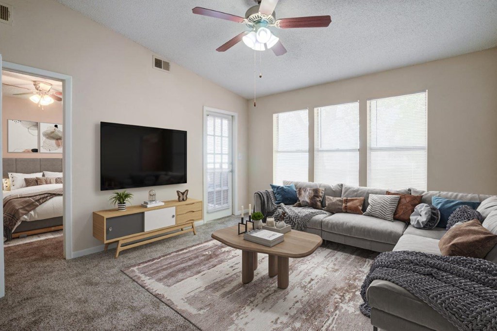 a living room with a ceiling fan and a television