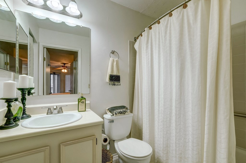 a bathroom with a white shower curtain and a toilet and sink