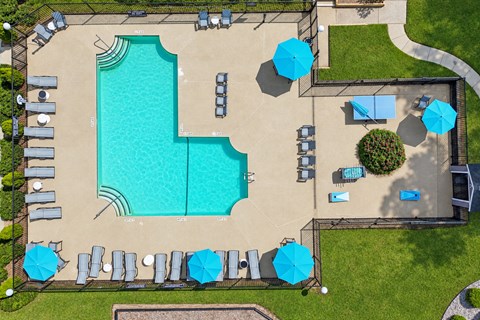 A large swimming pool surrounded by blue umbrellas and lounge chairs.