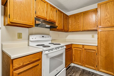 A kitchen with wooden cabinets and a white stove top oven.