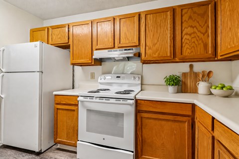 A white refrigerator and stove in a kitchen with wooden cabinets.