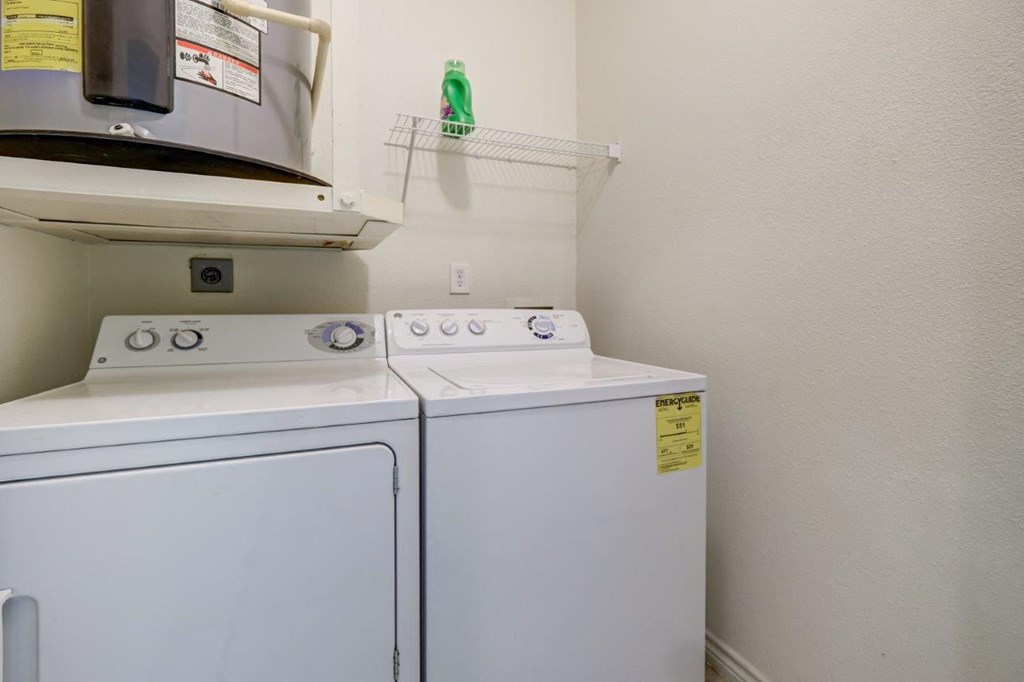 the laundry room has a washer and dryer and a shelf over thewasher
