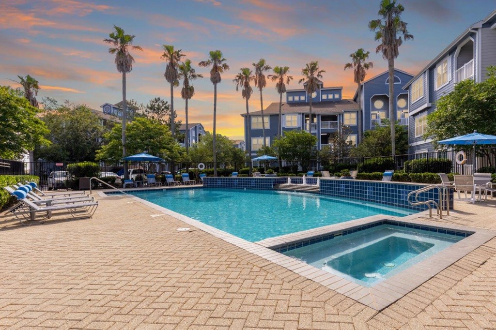 a swimming pool with palm trees and a building in the background