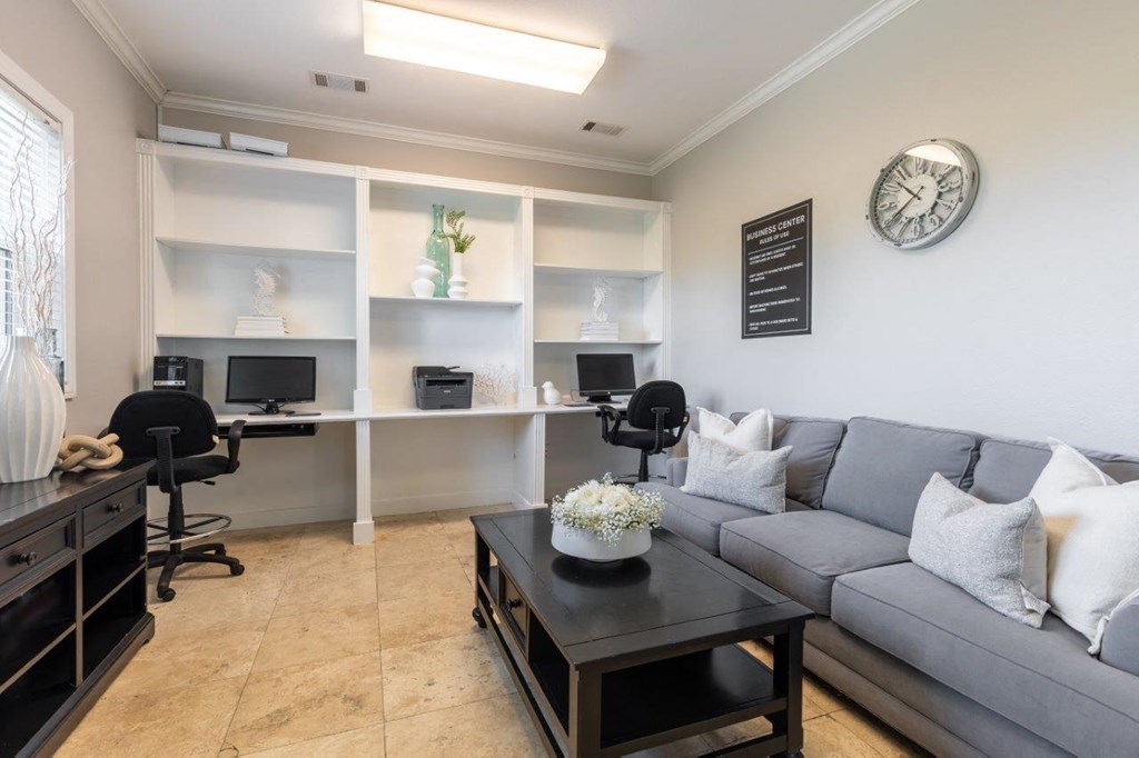 a living room with a couch and a desk with two computers