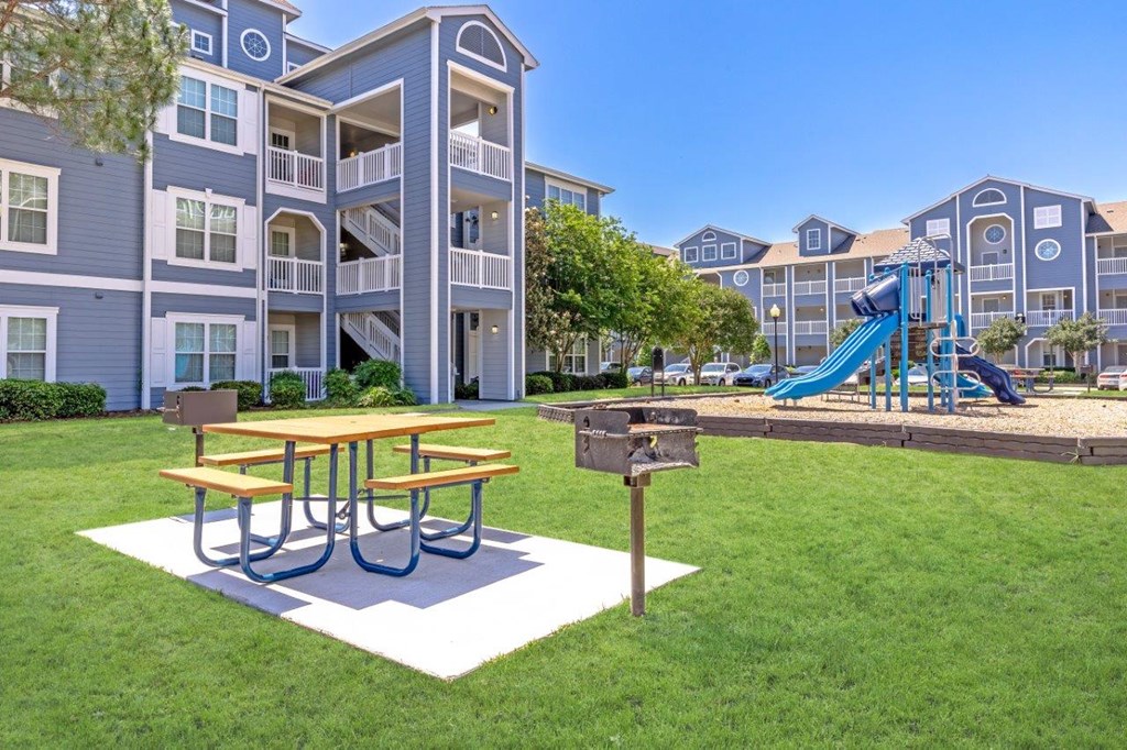 a playground and picnic table in front of an apartment building