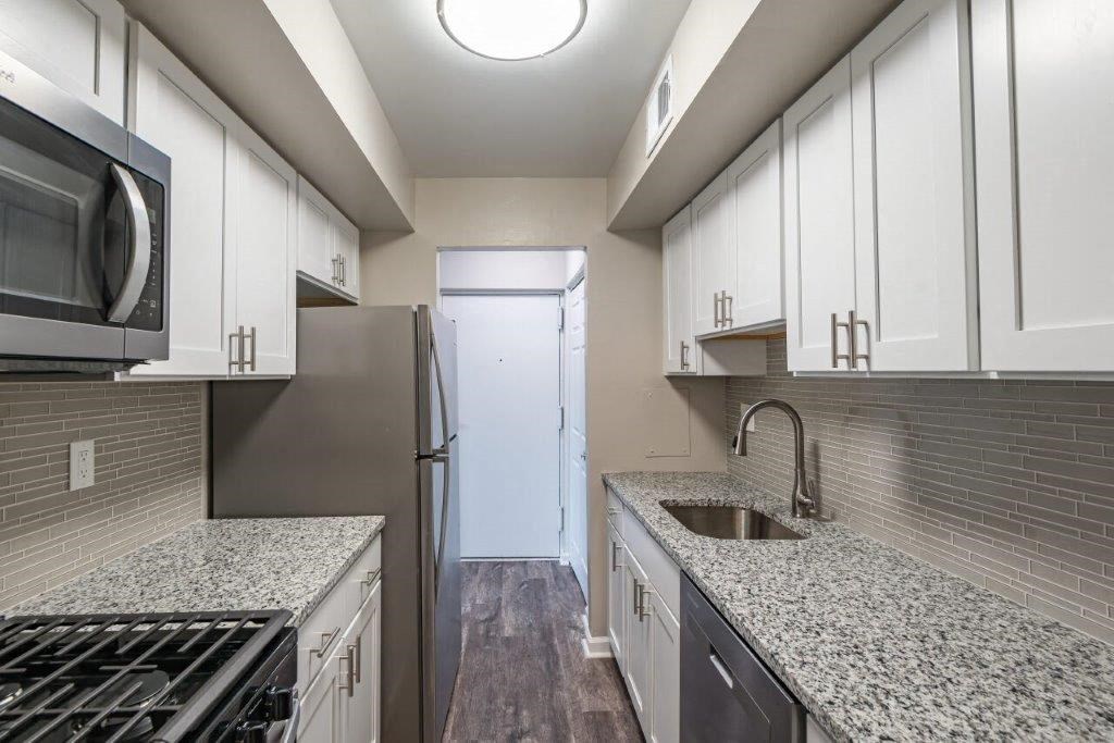 a kitchen with marble counter tops and white cabinets